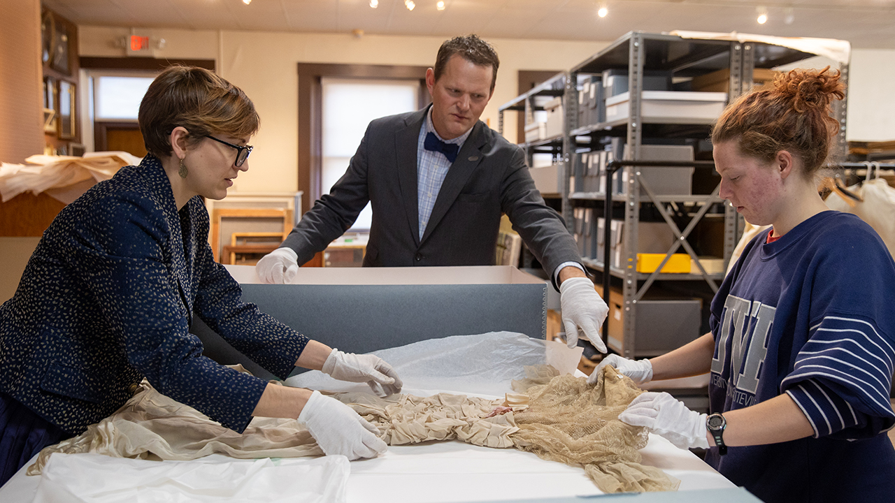 Senior Lecturer Sarah Strange, Associate Professor Dr. Eugene Tesdahl and Emma Larsen examine an original garment.