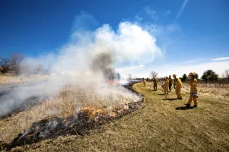 Photo of team in front of field fire on campus.