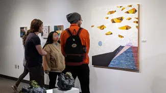 Three students looking at artwork in a gallery