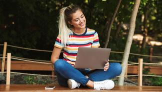 online student outside on laptop