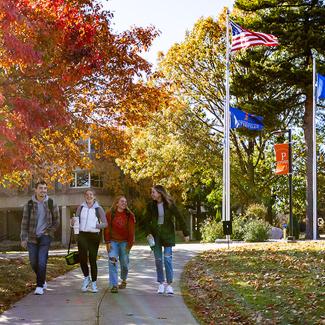 students walking across campus with UWP flags in background