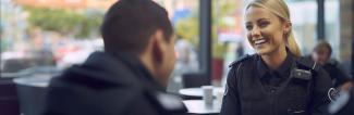 Smiling female police officer speaks to colleague