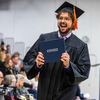 UW-Platteville student holding diploma at graduation commencement ceremony